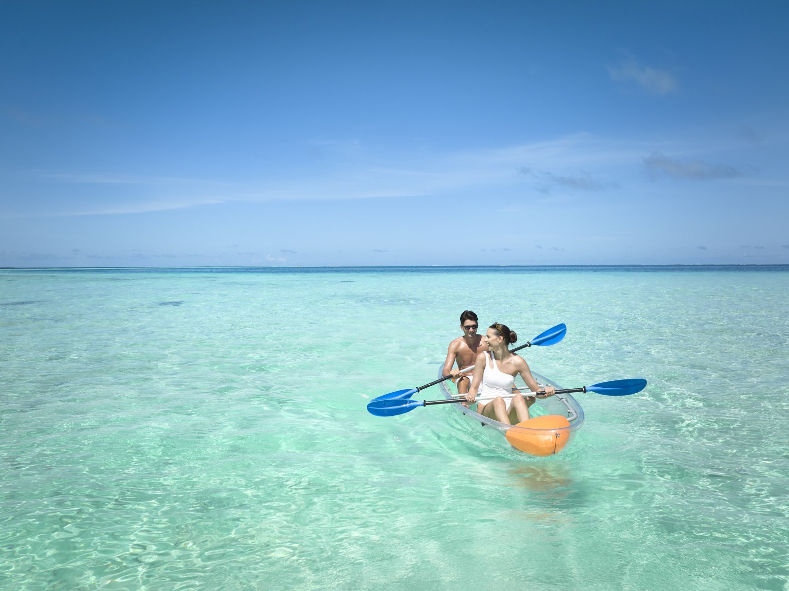 Guests kayaking in the lagoon with overwater villas behind