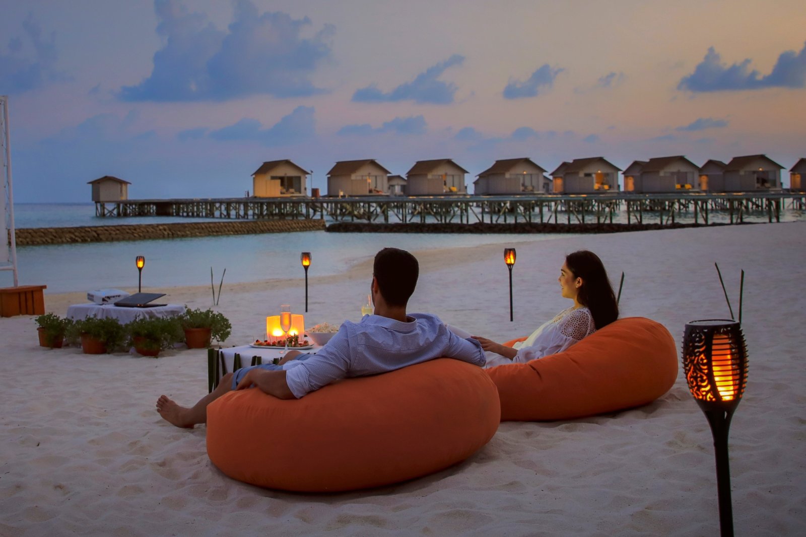 Beach seating at dusk with overwater villas behind