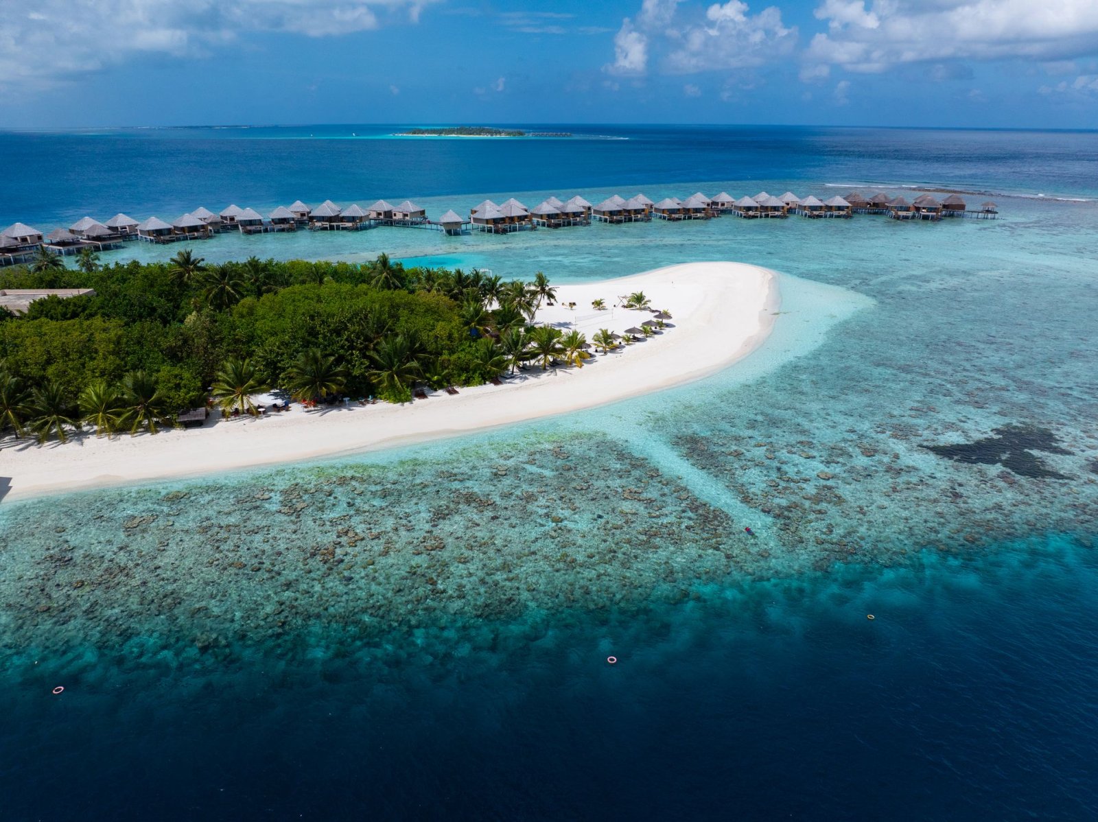 Aerial view of the white-sand beach and overwater villas