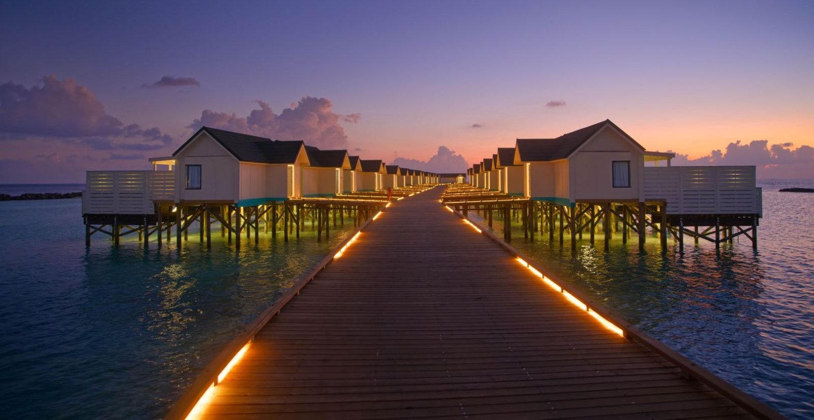Water villa jetty lit at dusk