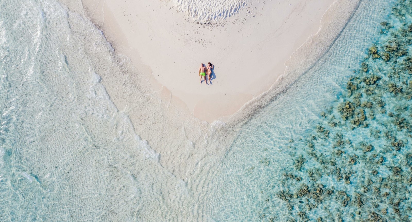 Aerial view of a couple on a white-sand spit